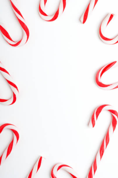 istock Blank frame with Christmas candy canes top view. New Year lollipops on white background. Winter holidays backdrop with copyspace. Xmas confection composition with decorative elements. 1185266451