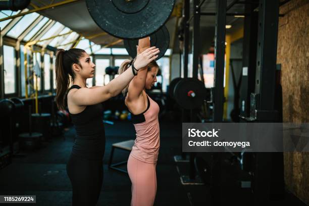 Woman Lifting Weights With A Help Of Fitness Instructor Stock Photo - Download Image Now