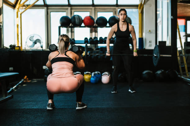 istock Two young women lifting weights in the gym 1185269413