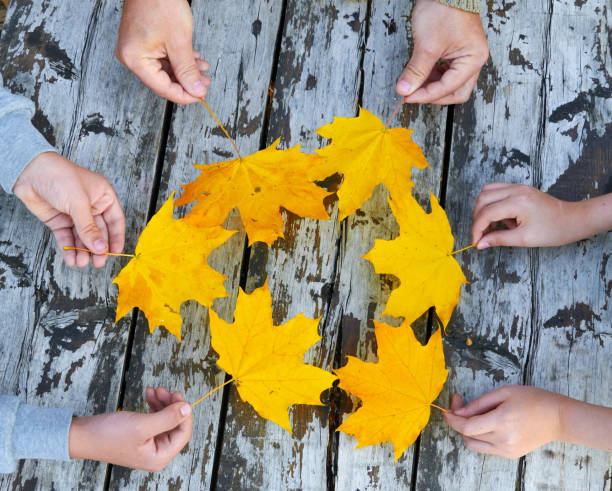 istock Hands with Autumn Leaves over wooden background 1185270712
