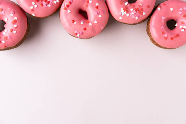 istock Different donuts with icing on pastel pink background. Sweet donuts, top view, flat lay. 1185272429