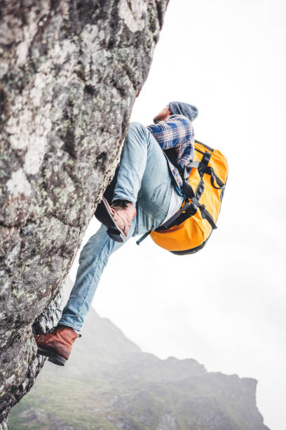 dzielny wspinacz z profesjonalnym plecakiem wspina się na skałę. aktywny nieustraszony rój turystyczny na górze - rock norway courage mountain zdjęcia i obrazy z banku zdjęć