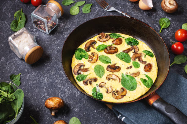 istock Omelette with mushrooms and spinach in iron pan on stone background. 1185282551