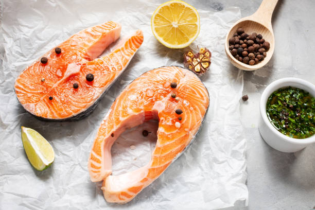 istock Two fresh raw salmon steaks with salt, peppers, lemon on concrete background 1185291699