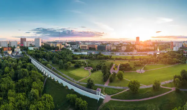 Aerial view of Moscow over the Rostokino Aqueduct (Millionny Bridge) and the park around it at summer sunset. There are distant VDNKh park and Ostankino tower