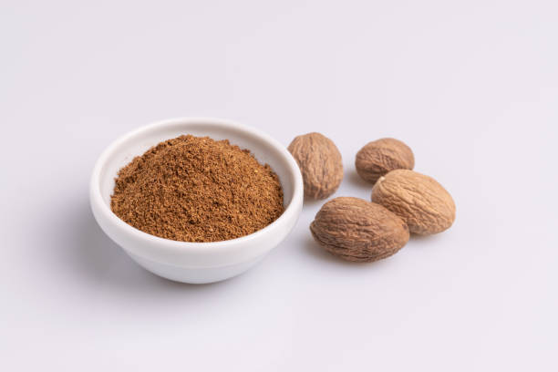 istock Ground nutmeg spice in white ceramic bowl isolated on white background, soft light, studio shot, copy space. 1185296292