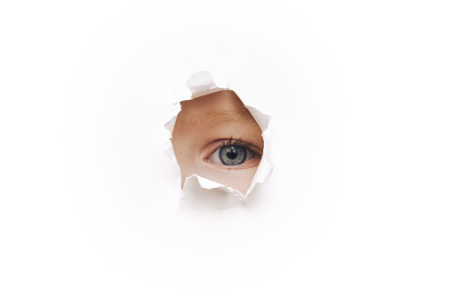 Voyeurism. The child is watching the parents. A curious child look. Spying on or overhearing the concept. Hole on White paper.