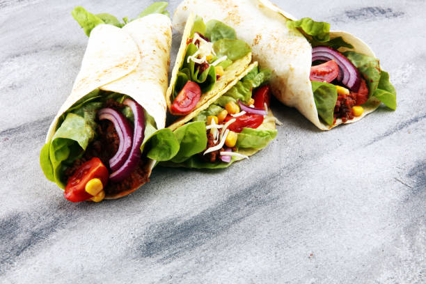 istock Mexican food, including tacos, guacamole, nachos and pepper on rustic table 1185297723