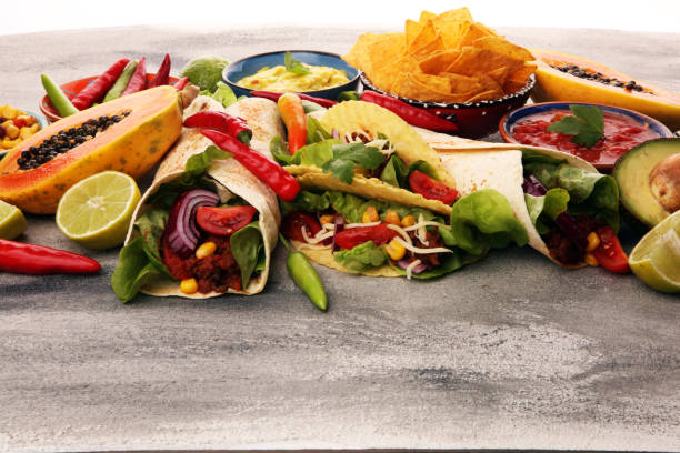 istock Mexican food, including tacos, guacamole, nachos and pepper on rustic table 1185297882