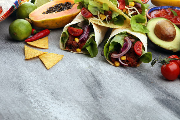 istock Mexican food, including tacos, guacamole, nachos and pepper on rustic table 1185299058