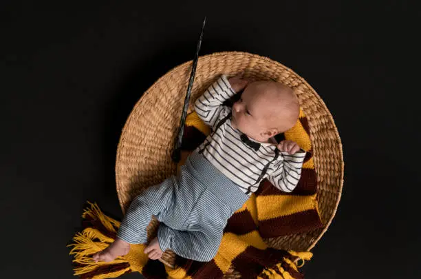 Little newborn baby boy like in a magic book in halloween time. Magic wand, black background and scarf