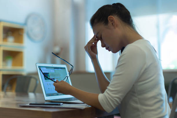 Tired stressed out woman working on her computer. Business. Exhausted and stressed out woman taking a break from the computer, rubbing her sore eyes. managing stress stock pictures, royalty-free photos & images