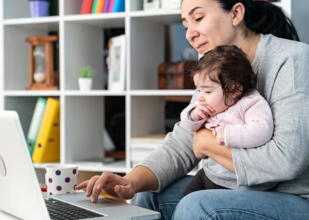 istock Mother Working From Home While Holding Her Baby In Living Room 1185306768