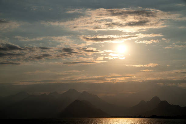 Seascape of Mediterranean Sea during sunset. No people are seen in frame. Sun is seen behind clouds. Shot with a full frame mirrorless camera.