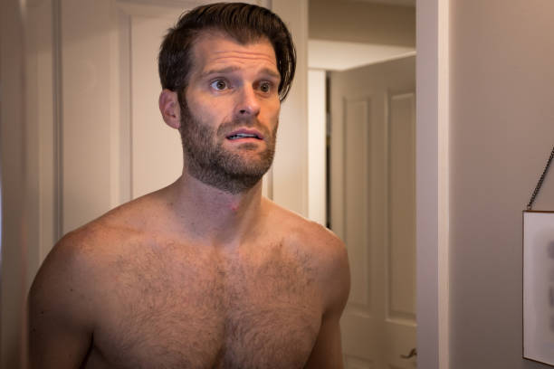 istock A middle aged caucasian man with a unhappy expression looking at himself in a mirror. 1185308547