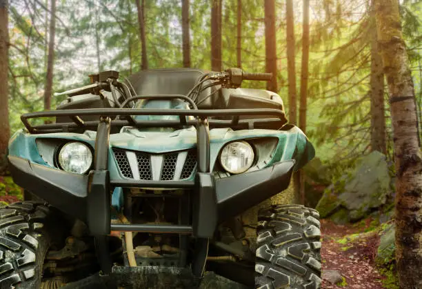 Photo of a green offroad hunting atv vehicle standing in forest, front view.