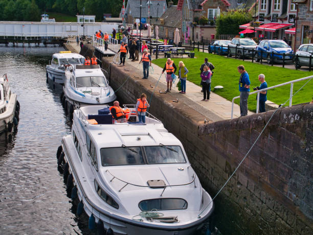 Leisure cruiser boats pass through the staircase locks at Fort Augustus in the Great Glen, Scotland, UK Leisure cruiser boats pass through the staircase locks at Fort Augustus in the Great Glen, Scotland, UK - a Canal & River Trust official (in blue) oversees. fort augustus stock pictures, royalty-free photos & images