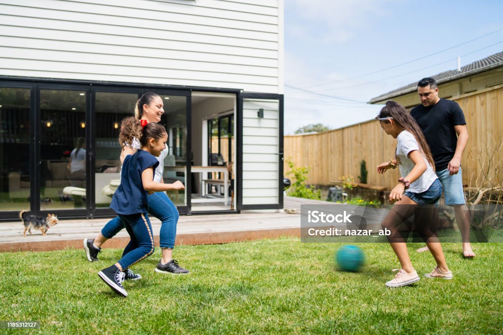 Parents playing soccer with kids in backyard. Playing soccer in backyard in Auckland, New Zealand. Family Stock Photo