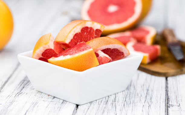 istock Sliced Grapefruits on an old wooden table (selective focus) 1185313483