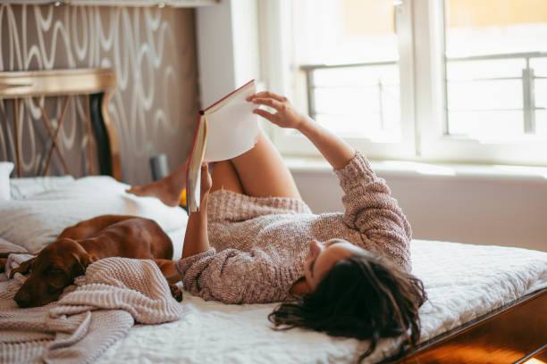 istock Young woman reading and resting with her dog 1185316433
