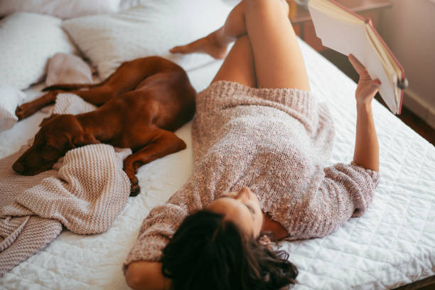 istock Young woman reading and resting with her dog 1185316709