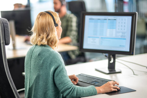 istock Blonde woman using a computer and wearing a headset 1185316855