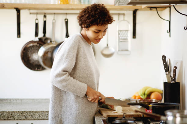 istock young woman cutting vegetables with knife in kitchen 1185317160