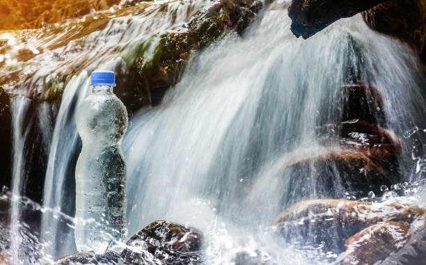 istock Plastic water bottle standing near streaming waterfall. 1185317578