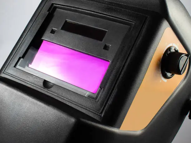 Photo of a black welding helmet close-up view on light background.