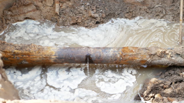 close-up of leakage in city sewage system ot water pipeline. water coming from broken metallic tube
