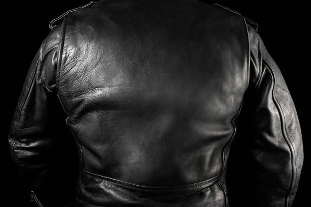 Black leather biker jacket standing black background rear view. stock photo