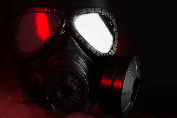 Photo of a black military gas mask with red highlights laying on black background.