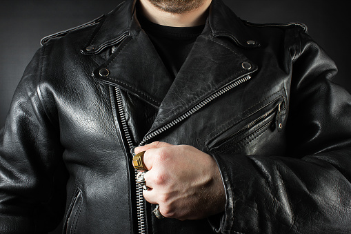 Photo of a man in black leather biker jacket and rings closeup view on black background.