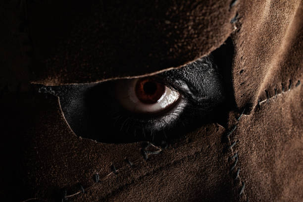 Clouseup photo of a evil monster murderer eye face part in sewed leather mask on black background.