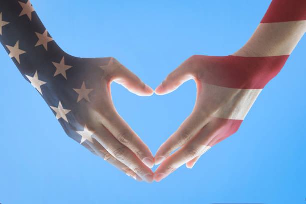 istock America flag pattern on people's hands in heart shape on blue sky background 1185324276