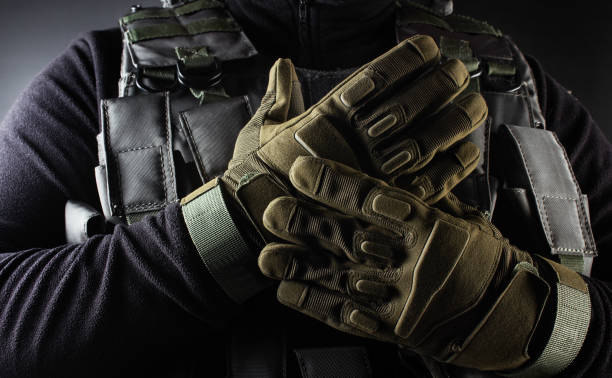 Soldier in black armor tactical vest and gloves standing. Photo of a fully equipped soldier in black armor tactical vest and gloves standing on black background closeup front view. khaki green photos stock pictures, royalty-free photos & images