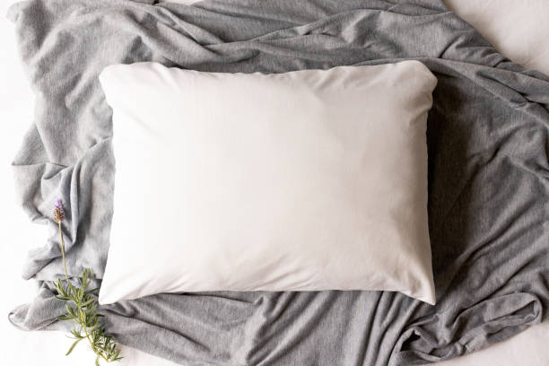 istock Plain white pillowcase on a grey and white textile background with lavender sprig 1185325308