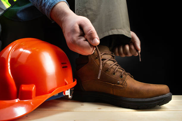 Worker lacing up leather boot on a surface. stock photo
