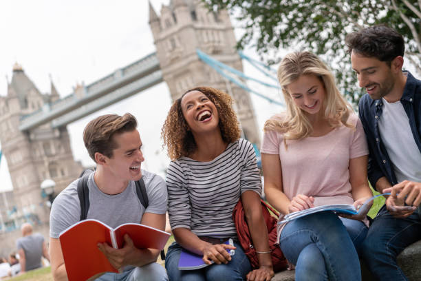 Happy group of students having fun studying outdoors in London and laughing - education concepts