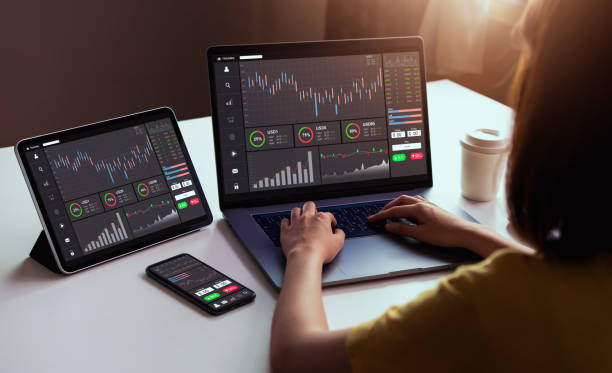 Stock exchange market concept, businesswoman trader looking on laptop and tablet, smartphone with graphs analysis candle line in office room, diagrams on screen. stock photo