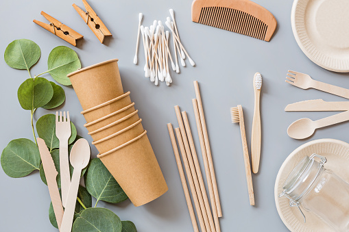 eco natural paper coffee cups, straws, toothbrushes, plates, comb, clothespins flat lay on gray background. sustainable lifestyle concept. zero waste, plastic free items. stop plastic pollution. Top view, overhead, mock up, template