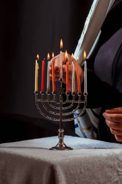 istock Man hand lighting candles in menorah hanukka lights candles 1185331691