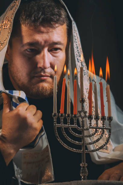 uomo ebreo con barba che accende le candele in preghiera di una menorah accende candele hanukkah - hanukkah menorah human hand lighting equipment foto e immagini stock