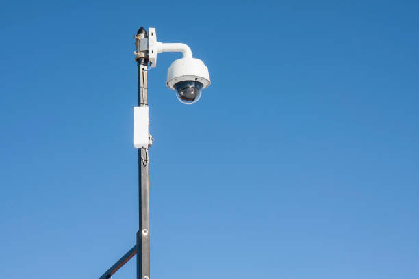 istock Pole equipped with white surveillance camera against blue sky 1185332714