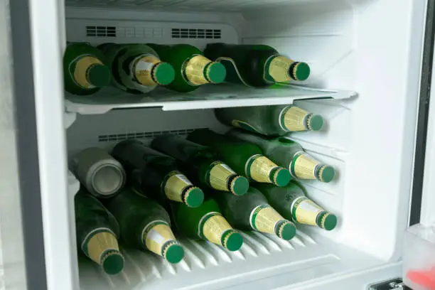 Photo of Bottles full of beer in a refrigerator.