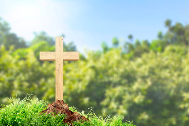 Christian cross on the ground with green grass over blue sky background