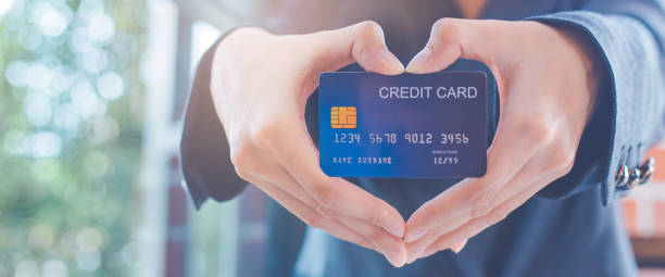 Female businessmen are holding a credit card and making a heart-shaped hand. stock photo