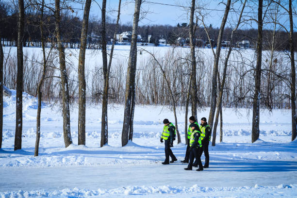 A group of Canadian policemen on patrol during the winter time. Police officers in investigation mission near a frozen river. stock photo