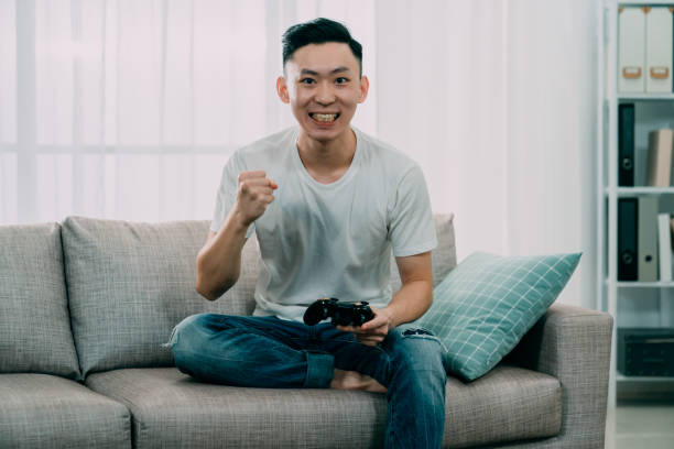 istock korean man raised fists up win video game. 1185344891