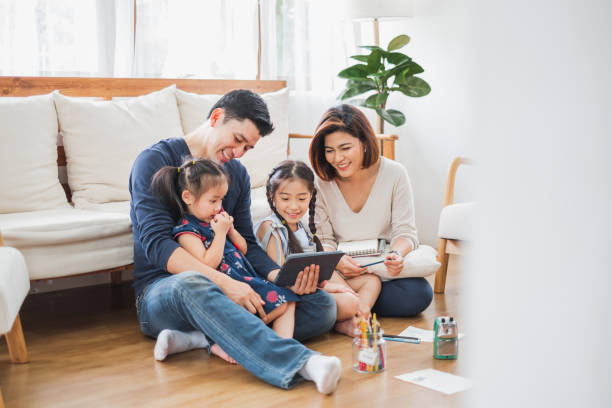 happy asian family using tablet, laptop for playing game watching movies, relaxing at home for lifestyle concept - father digital tablet asian ethnicity daughter imagens e fotografias de stock